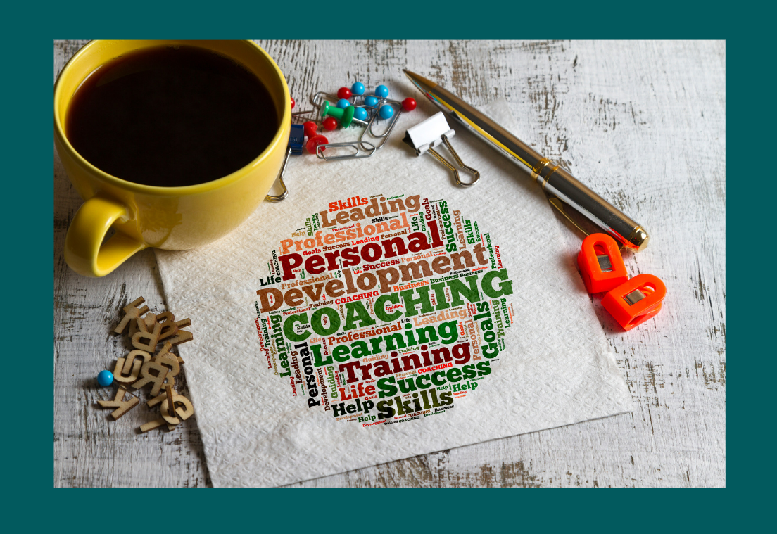 A cop of coffee next to small desk objects and a napkin with lots of coaching words including development, success, life skills and more