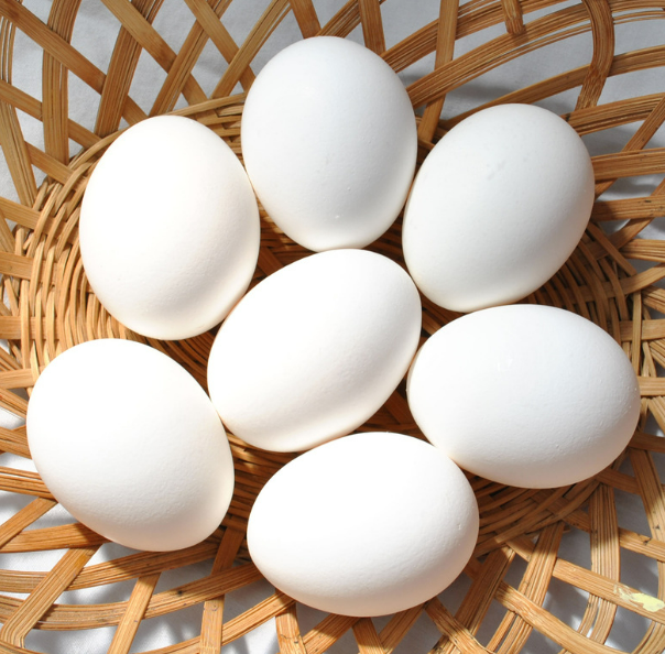 7 white eggs in a wooden basket 