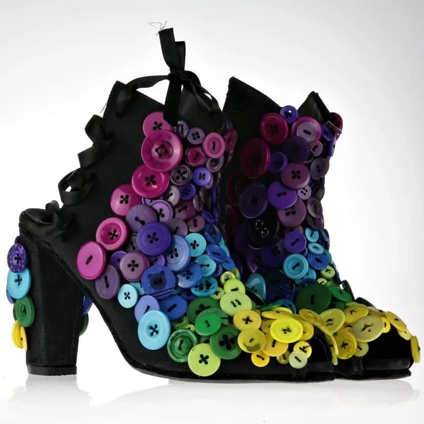 Pumps with open toe and open heel in black cotton fabric  with a 10cms heel. The front is 5cm above the ankle area covered in buttons with various shades starting toe to top: yellow, green, blue and purple. The heel is covered in a mix of buttons as well. The back side has silk lacking to help with holding the shoes in place around the ankle and leg