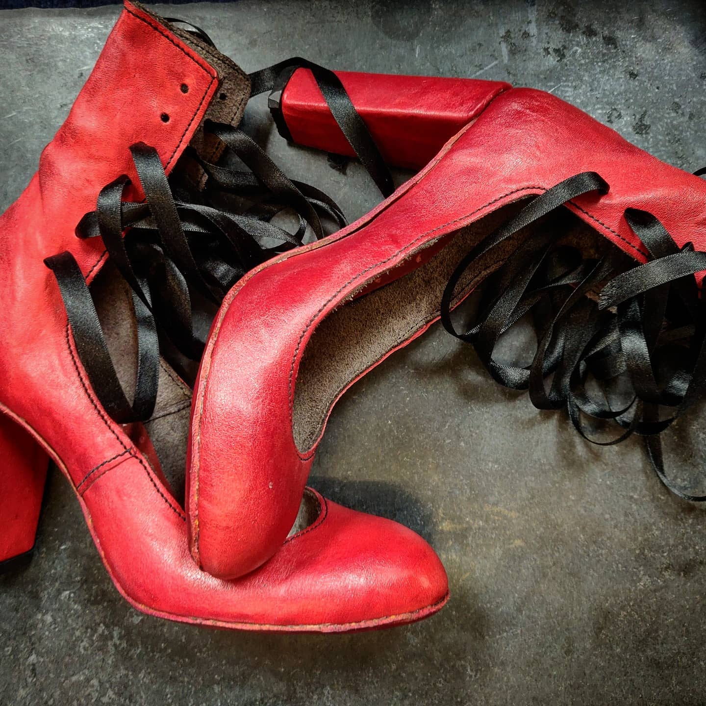 Side view of the shows focusing on the contrast of vibrant red leather and silk black of the lace