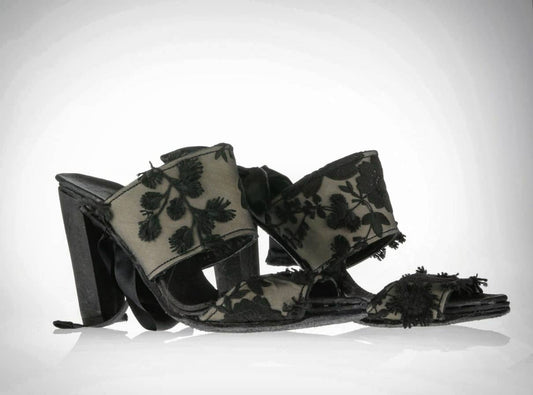 Sandals/pumps with a 10cm block heel and two chunky straps on the front. Each strap is in nude leather covered in 3D black lacing with elaborate flowers and leaves. The pair also has a silk ribbon starting under the sole and going up the leg. Alternately it can be tied around the heel or under the sole for different styles of wearing these