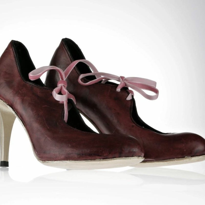 Burgundy leather pumps inspired by a ballerina shoe. Has 3 eyelids holes at the front to be tied in a soft pink ribbon. The sole is gold and this particular pair has a gold stiletto heel, thou they come in a block heel option too.