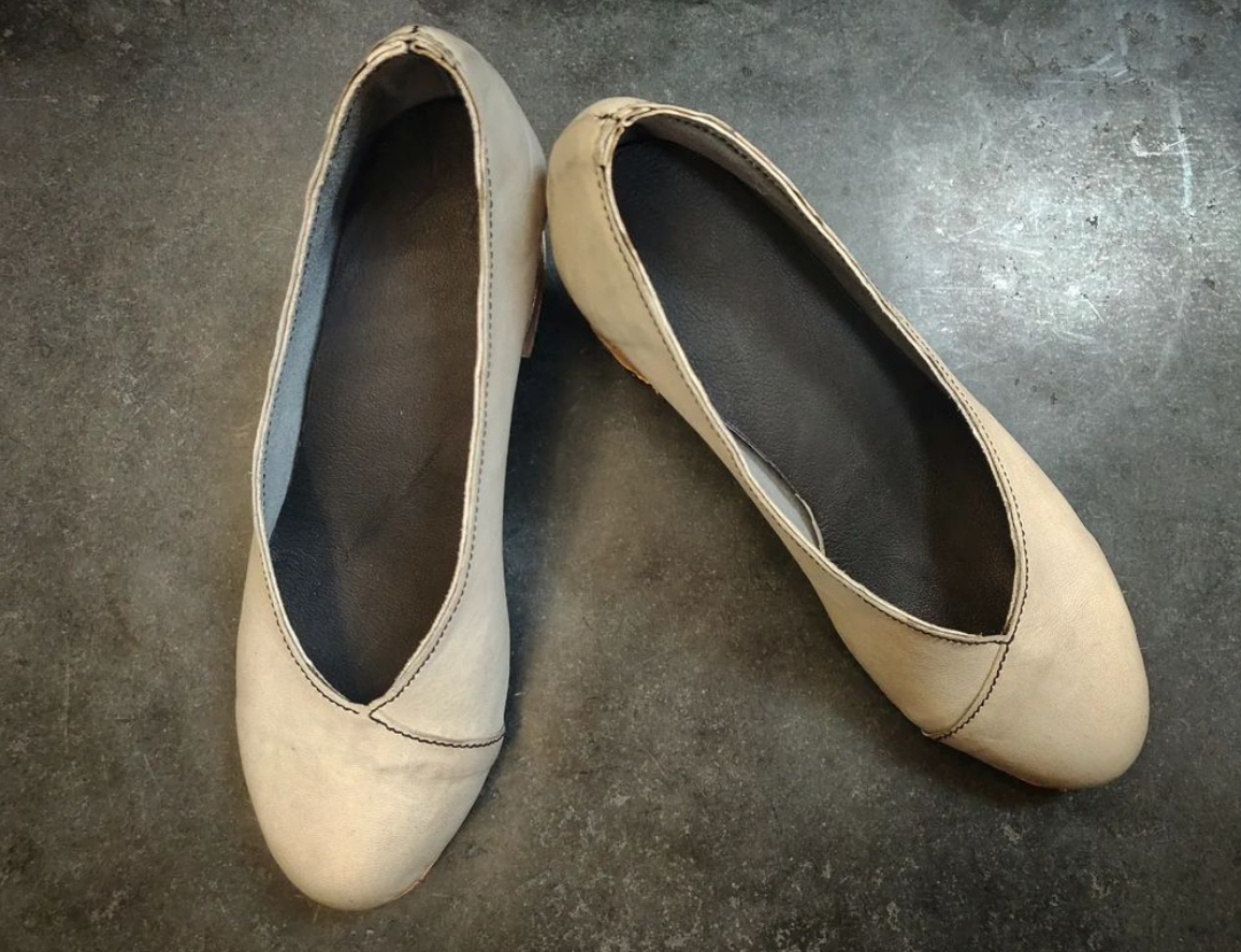 Pair of pumps in a soft grey leather with asymmetrical sides - straight on one side and slightly curved on the other. The sides come together with a wrap over the vamp area. The leather is so delicate and soft that this shoe for spring, summer as opposed to the colder weather