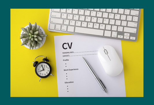 A photo of a CV on a yellow desk alongside with a keyboard, mouse, pen, plant and clock