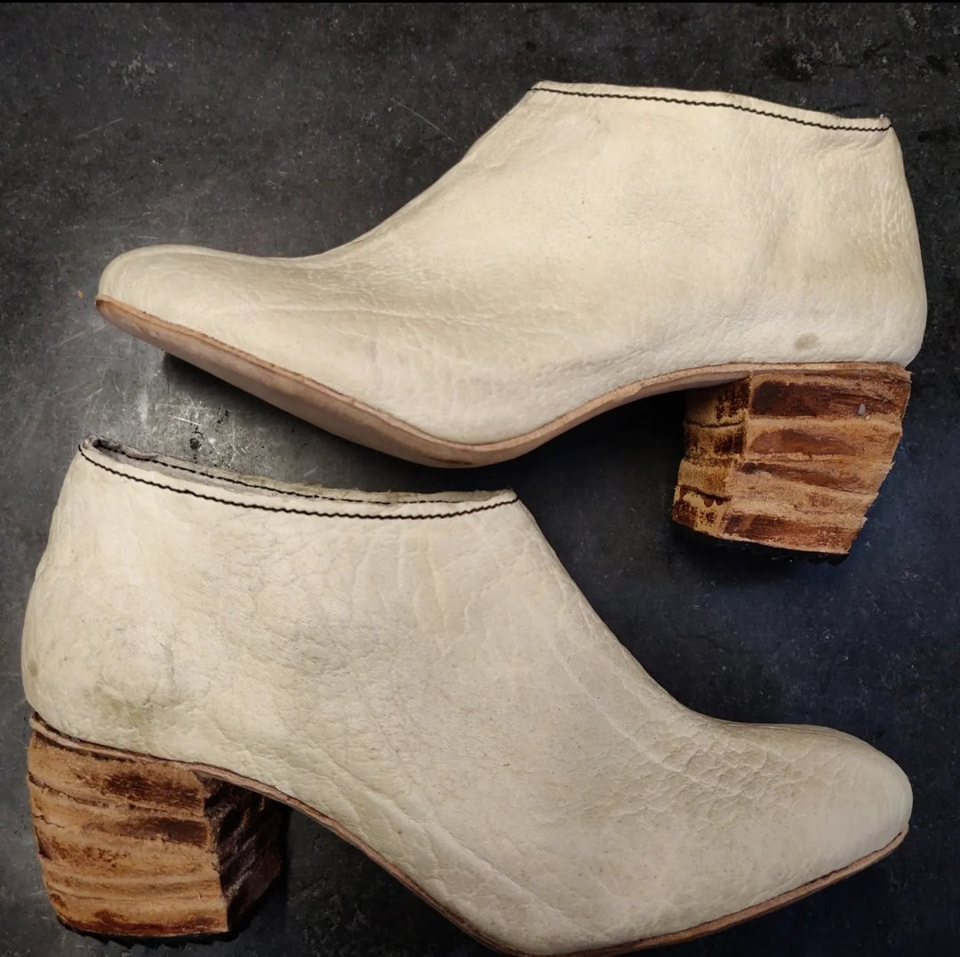 Lateral view of the shoes with the focus on the multi panel leather heel in natural tan colors 