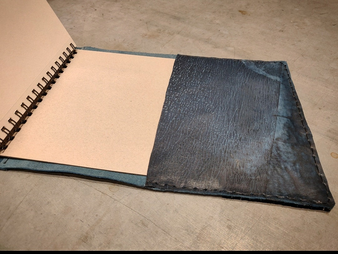 Blue cracked leather journal with the pages open to showcase the inside in the same leather and hand stitch 