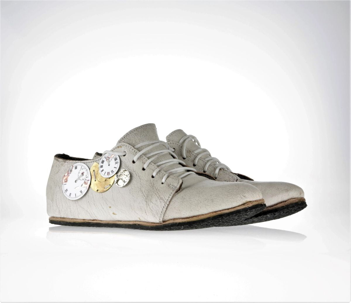 Lateral view of one of the shoes with the focus on the clock pieces - different sizes and colors (white and gold)