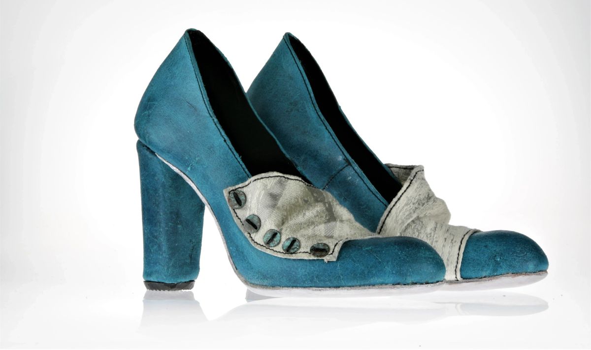 Pair of blue leather pumps with white/grey fabric around the vamp with oxygenized 5 copper buttons on each side. The heel is block and covered in the same blue leather and the sole is silver