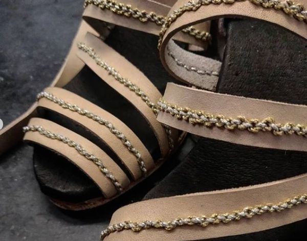 Close up detail of the straps and the hand sawn decorative chains in gold and silver thread on each of them 